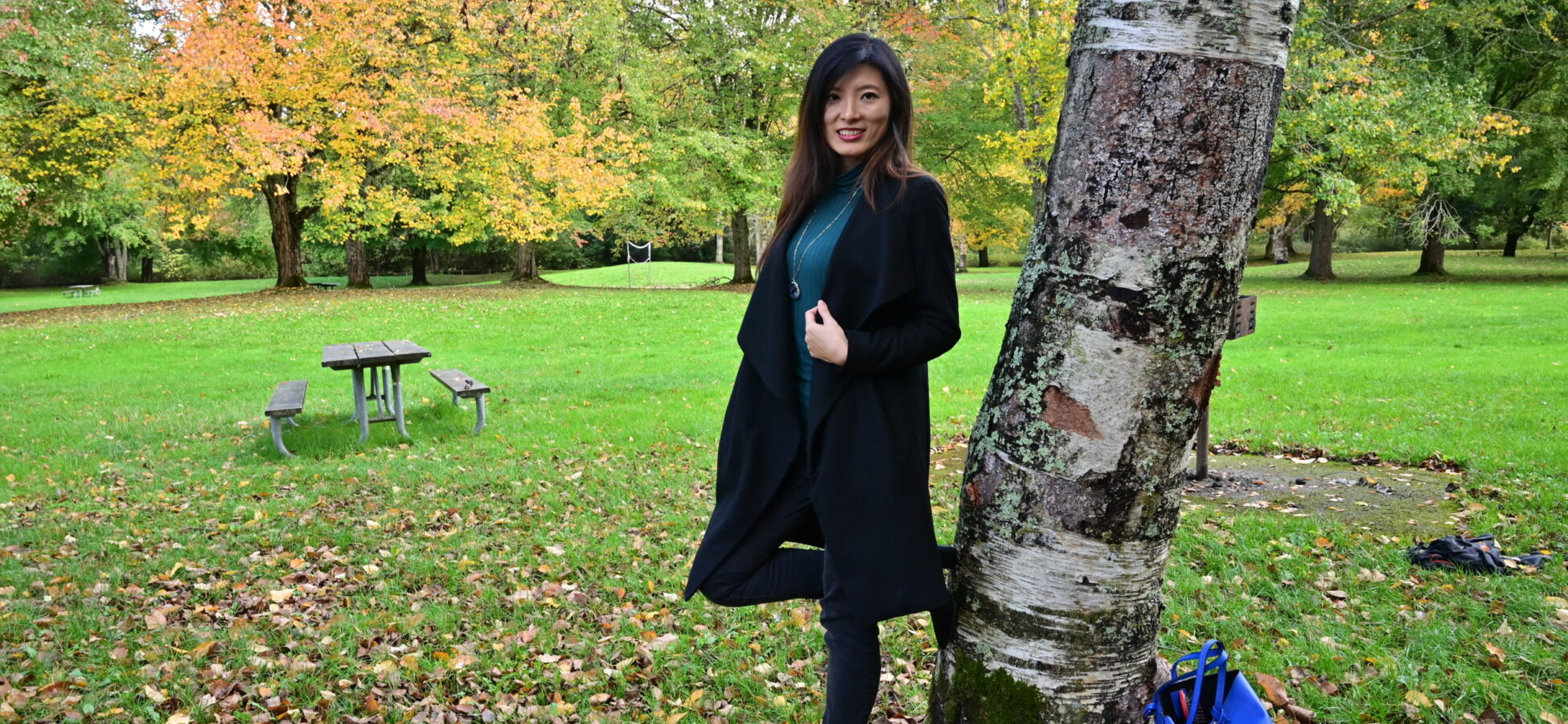 A Career and Relationship Coach standing near a tree in a peaceful setting, in front of a beautiful park.
