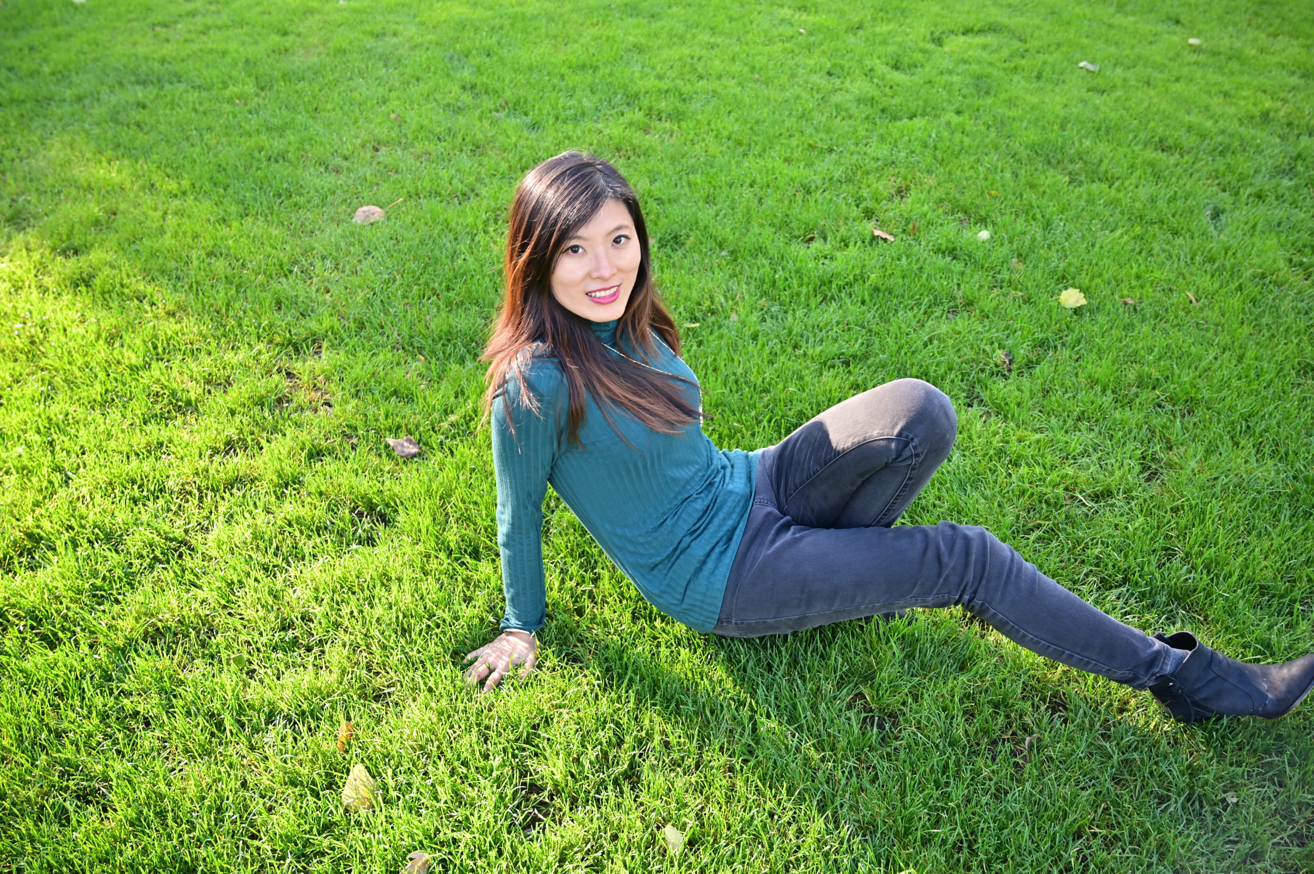 Coach Sixu wearing a green sweater is enjoying a relaxing moment on the grass.
