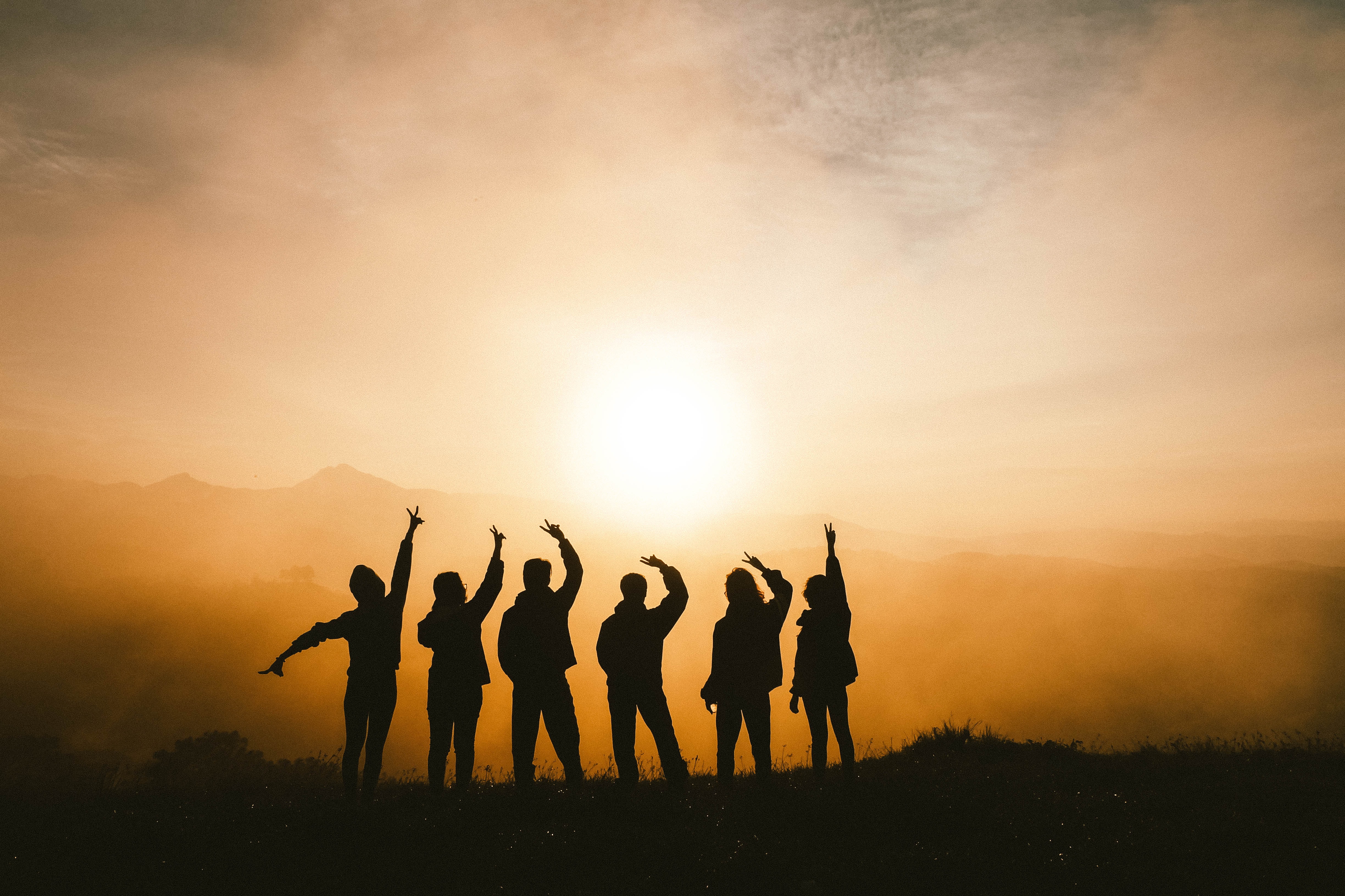 A breathtaking sunset view from the top of a mountain, with a group of people standing in silhouette.